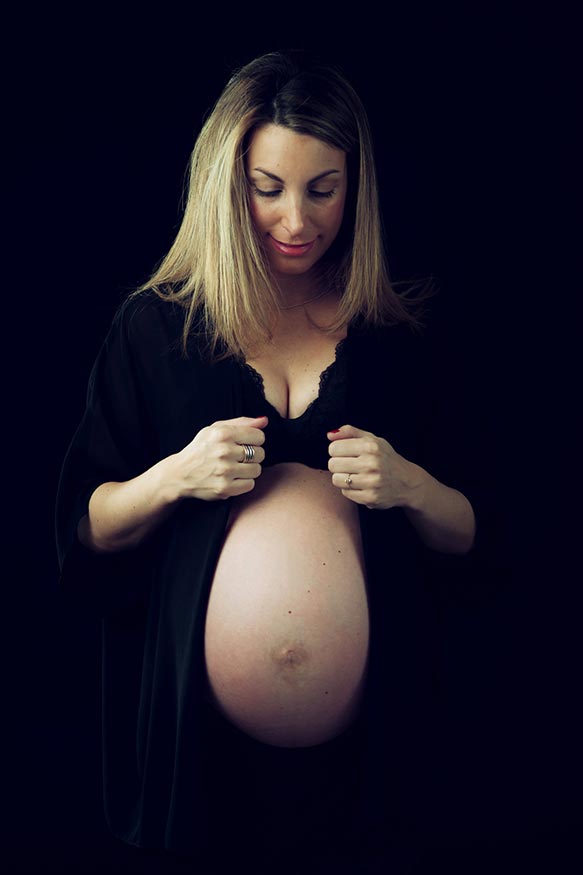Foto de mujer embarazada sobre fondo negro con ropa negra