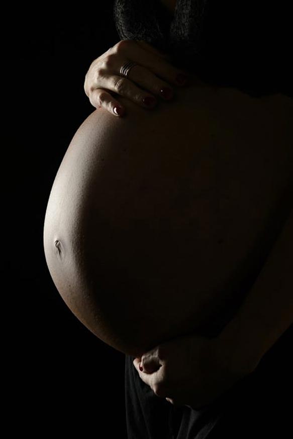 Fotografía barriga de embarazo sobre fondo negro