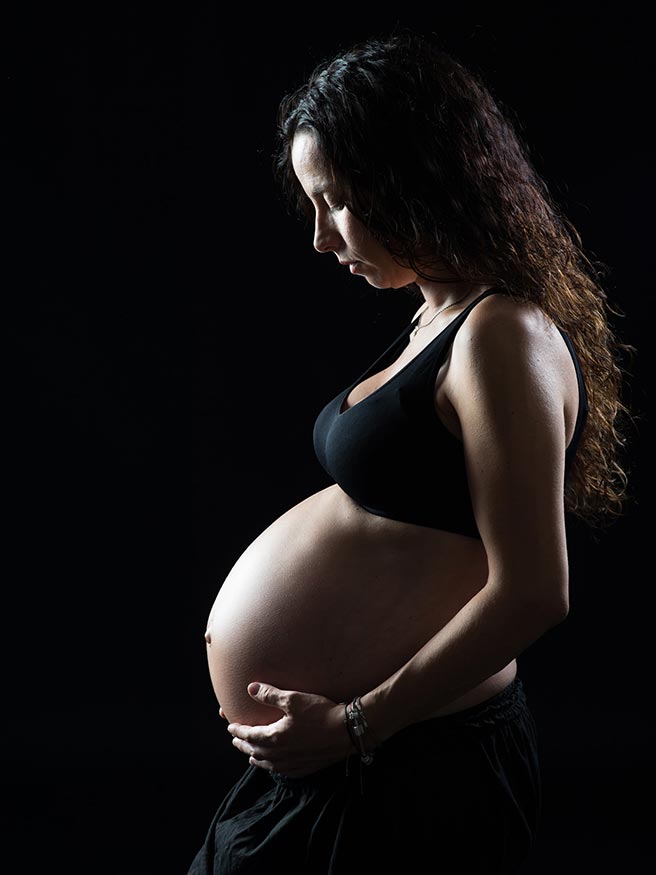 Mujer embarazada sobre fondo negro