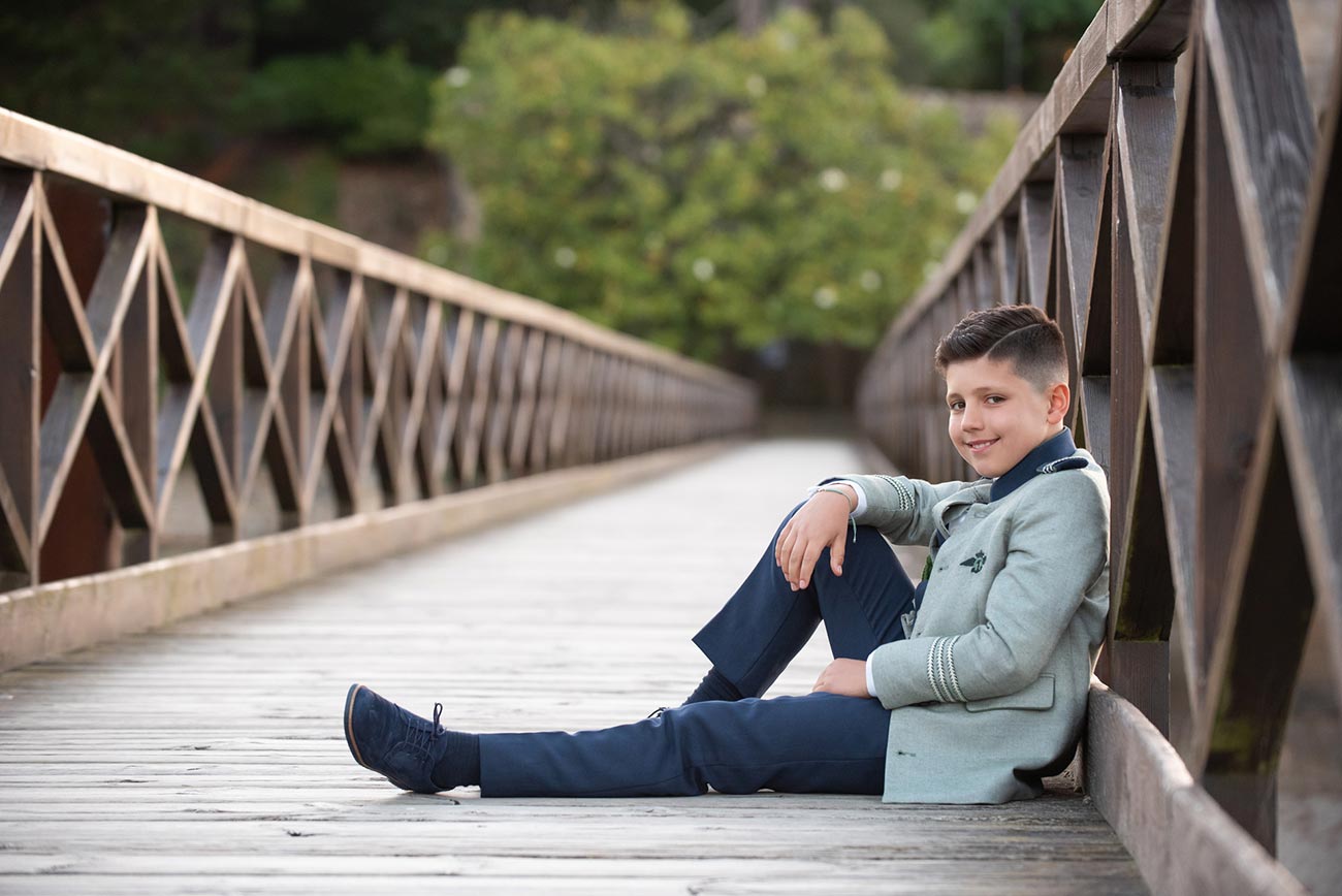 Niño sentado en un puente el día de su primera comunión